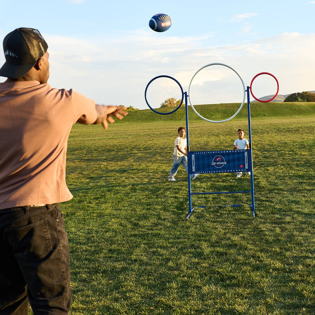 Quarterback throws a football toward the rings while two kids wait to catch on the other side